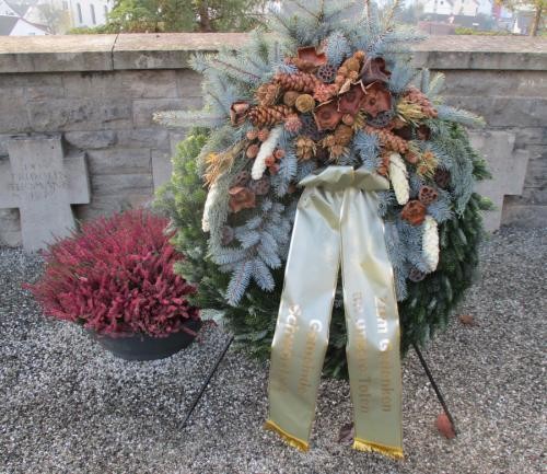 Das Bild zeigt einen niedergelegten Kranz mit goldener Schleife auf dem Friedhof in Schwörstadt.