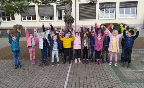 Das Bild zeigt jubelnde Kinder vor dem neuen Kinderbildungszentrum.